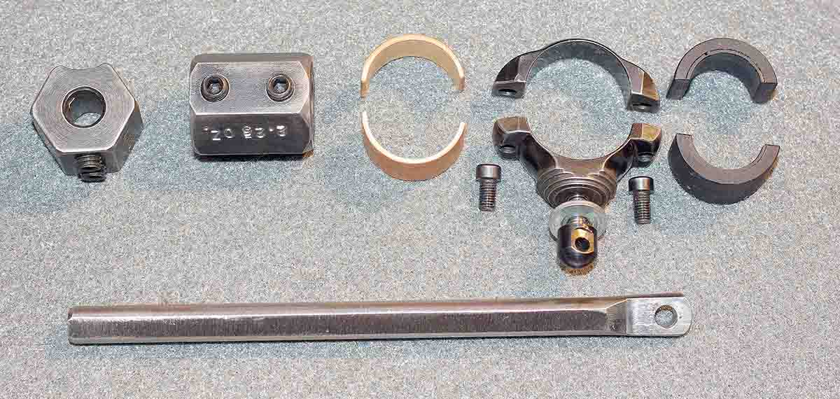 This view of the BMC disassembled shows its basic parts. From Left: 1.5- and 2.5- ounce sliding weights, larger barrel bushing, barrel attaching collar (made from a Redfield scope ring), with horizontal rod attaching bolt, smaller barrel bushing,  horizontal weight support rod.